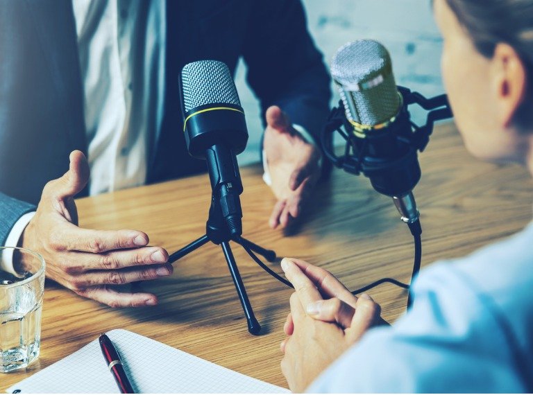 Two people speaking into microphones during an interview